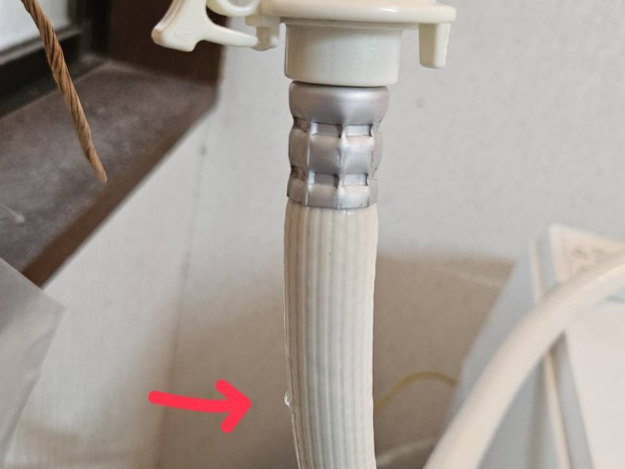 給水ホースを伝って水滴が落ちている。赤い矢印の先が水滴